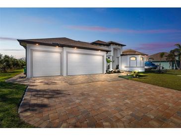 Stunning new home features a brick paver driveway, lush landscaping, and a three-car garage at 9533 Arnaz Cir, Port Charlotte, FL 33981