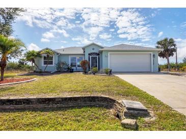 Inviting one-story home featuring a well-manicured lawn, lovely landscaping, and an attached two-car garage at 10307 Grail Ave, Englewood, FL 34224