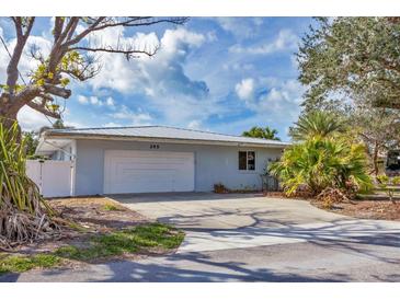Charming single-story home with a lush, tropical front yard and attached two-car garage at 295 North Dr, Englewood, FL 34223