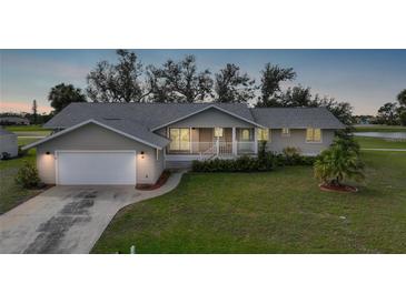 Charming single-story home featuring a well-manicured lawn and inviting covered porch at 18 Pebble Beach Road, Rotonda West, FL 33947