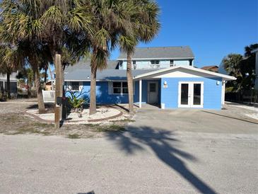 Charming blue single-story home with a well-manicured front yard and a sunny blue sky at 120 Stanford Dr, Englewood, FL 34223