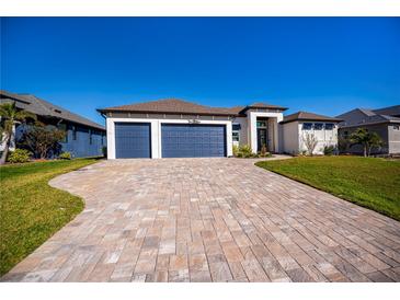 Stunning exterior showcasing a home with a blue three-car garage and beautiful paver driveway at 14718 San Domingo Blvd, Port Charlotte, FL 33981