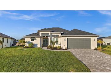 Beautiful home featuring a well-manicured lawn, paver driveway, and neutral color palette at 15044 Acorn Cir, Port Charlotte, FL 33981