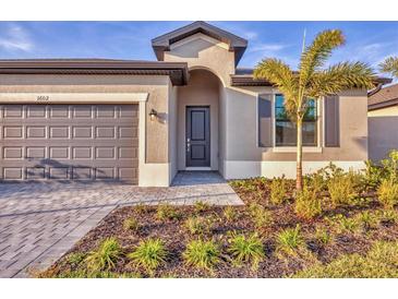 Charming single-story home with a gray garage door, walkway, and beautiful front yard landscaping at 1602 Saddlewood Cir, Port Charlotte, FL 33953