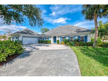Charming single-story home with a long driveway, blue shutters, manicured lawn, and beautiful landscaping at 17 Dominica Dr, Englewood, FL 34223