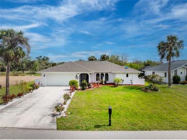 Charming single-story home with manicured lawn, mature palm trees, and a well-maintained driveway at 184 Eppinger Dr, Port Charlotte, FL 33953