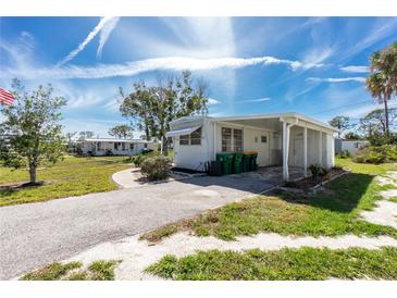 Charming mobile home featuring an extended driveway, covered porch, and well-maintained lawn, offering comfortable living at 3210 Holly Ave, Englewood, FL 34224