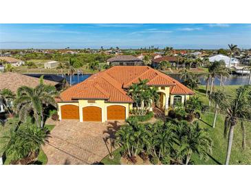 Stunning waterfront home with a three-car garage, lush landscaping, and beautiful terracotta roof at 8264 Antwerp Cir, Port Charlotte, FL 33981