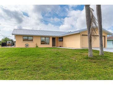 Charming single-story home with a well-maintained lawn, a metal roof and mature landscaping at 10075 Bentley Ave, Englewood, FL 34224