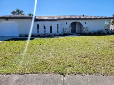 Charming single-story home featuring a lush green lawn and unique architectural details at 1247 Price Nw Cir, Port Charlotte, FL 33948
