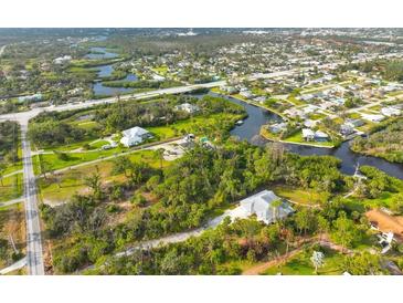 Expansive aerial view of a waterfront property with lush greenery and a winding canal at 150 N Oxford Dr, Englewood, FL 34223