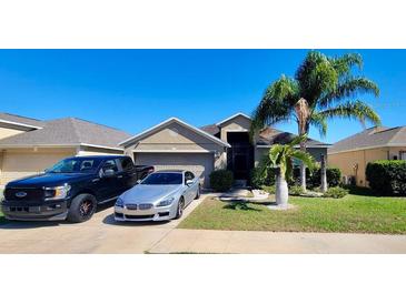 Inviting single-story home featuring a well-manicured lawn and mature palm trees, plus a two-car driveway at 15408 Feather Star Pl, Ruskin, FL 33573