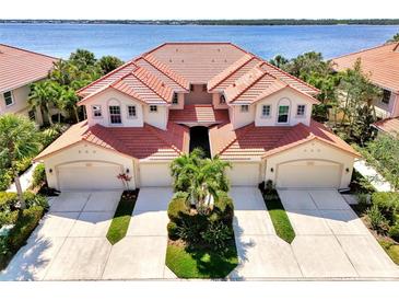 Stunning aerial view of the Mediterranean-style home showcasing the red tile roof and lush landscaping near the water at 4624 Club Dr # G201, Port Charlotte, FL 33953