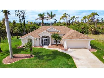 Beautiful single-story home with tan exterior, well-manicured lawn, and mature trees at 816 Rotonda Cir, Rotonda West, FL 33947