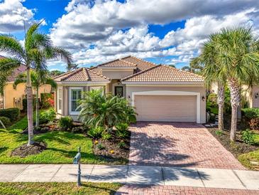 Charming single-story home featuring a brick driveway and a well-manicured lawn with lush tropical landscaping at 13112 N Marsh Dr, Port Charlotte, FL 33953