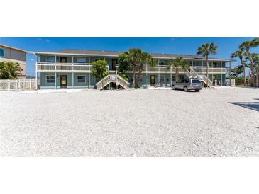 Beach condo building with palm trees and staircase entries to the units at 5041 N Beach Rd # 4A And 4B, Englewood, FL 34223