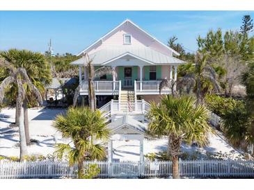 Charming elevated beach house with white picket fence and lush tropical landscaping at 14 Palm Dr, Placida, FL 33946