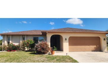 Charming single-story home featuring a well-maintained lawn, mature landscaping, and an attached garage at 171 Caddy Rd, Rotonda West, FL 33947
