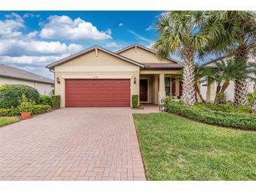 Charming single-story home featuring a red brick driveway, manicured lawn, and a red garage door at 2628 Sherman Oak Dr, North Port, FL 34289