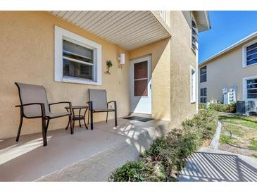 Cozy porch with seating and front door to a yellow home at 6610 Gasparilla Pines Blvd # 113, Englewood, FL 34224