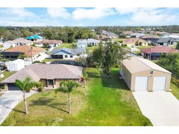 Expansive aerial view of a tan home with lush lawn, detached garage, and tropical landscaping at 9260 Saint Catherine Ave, Englewood, FL 34224