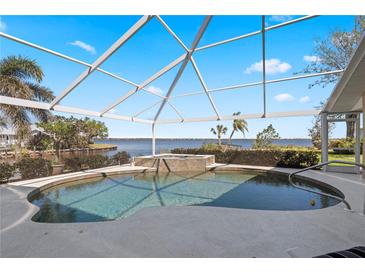 A screened in pool features a waterfall, with beautiful views of the water at 12432 Nova Ave, Port Charlotte, FL 33981