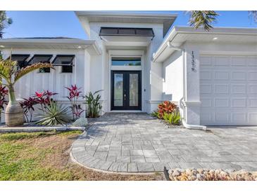 Beautiful single Gathering home featuring a well-manicured lawn, stone accents and a covered front entryway at 13379 Journal Ln, Port Charlotte, FL 33981