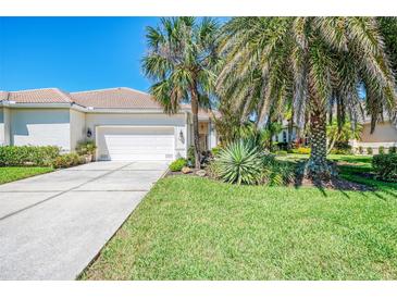 Charming home with a well-manicured lawn, mature palm trees, and a two-car garage at 14270 Reserve Ct, Port Charlotte, FL 33953