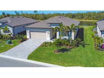Charming home with lush landscaping, brick paved driveway, and beautiful lake view in the background at 1758 Saddlewood Cir, Port Charlotte, FL 33953
