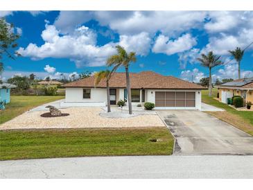 Charming single-story home featuring a well-manicured lawn, palm trees, and an attached two-car garage at 20 Bunker Way, Rotonda West, FL 33947