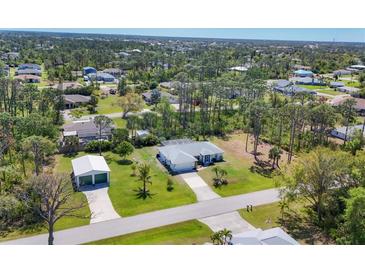 Aerial view of a single-Gathering home with a well-maintained lawn, mature trees, and a detached garage at 5258 Grassland Ter, Port Charlotte, FL 33981