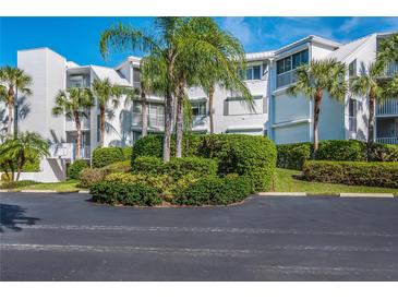 Exterior view of a white condo building surrounded by lush, manicured landscaping and tropical palm trees at 5858 Gasparilla Rd # Mm40, Boca Grande, FL 33921
