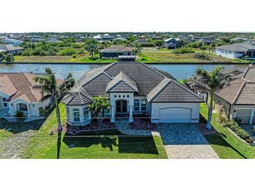 Beautiful exterior view of a one-story home featuring a tile roof, lush lawn, and waterfront access at 8144 Antwerp Cir, Port Charlotte, FL 33981