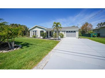 Charming home with well-manicured lawn, palm trees, and a long driveway leading to the garage at 9350 Prospect Ave, Englewood, FL 34224