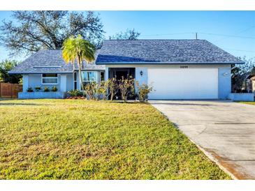 Charming single-story home boasts a well-manicured lawn, palm tree, and a two-car garage at 10299 Willmington Blvd, Englewood, FL 34224