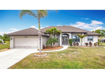 Charming single-story home with a manicured lawn, a two-car garage, and lush landscaping at 12605 Bacchus Rd, Port Charlotte, FL 33981