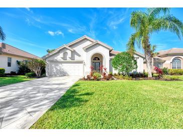 Charming home with lush lawn, palm trees, and a driveway leading to a two-car garage at 14236 Silver Lakes Cir, Port Charlotte, FL 33953