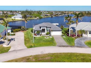 Inviting single-story home with a well-maintained lawn and waterfront views at 15498 Seafoam Cir, Port Charlotte, FL 33981