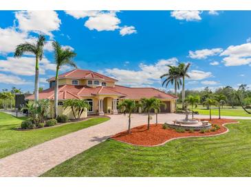 Stunning two-story home featuring lush landscaping, a fountain, and a brick driveway at 3700 Como St, Port Charlotte, FL 33948