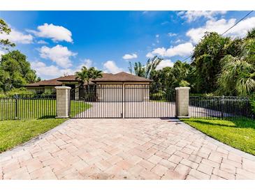 A beautiful paver driveway leads to an elegant home with decorative fencing and a manicured lawn at 4238 Golfair Ln, North Port, FL 34288