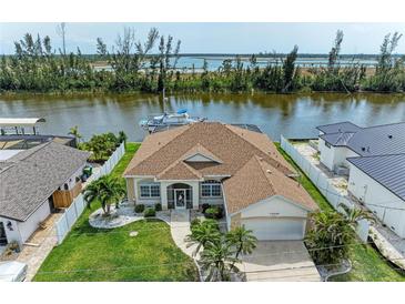 Waterfront home featuring a beautiful lawn, tropical landscaping, and convenient dock with boat lift at 10640 Ayear Rd, Port Charlotte, FL 33981