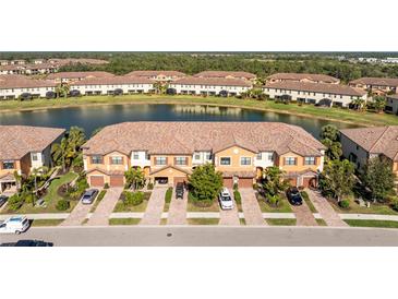 Scenic aerial view of townhomes by a lake with landscaped grounds and paver driveways at 20231 Lagente Cir, Venice, FL 34293