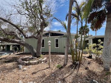 Charming exterior with mature trees and landscaping, and light green siding giving it a welcoming appeal at 2985 N Beach Rd # Bv-5, Englewood, FL 34223