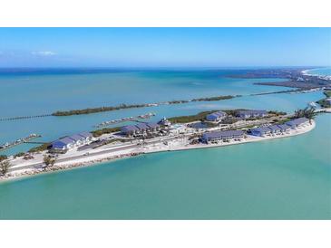 Stunning aerial view of a coastal property featuring multiple residences, boat docks, and beautiful turquoise water at 6040 Boca Grande Cswy # A2, Boca Grande, FL 33921