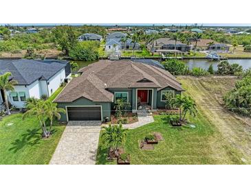 Beautiful home exterior featuring lush landscaping, a well-manicured lawn, and a paver driveway leading to an attached two-car garage at 8304 Antwerp Cir, Port Charlotte, FL 33981
