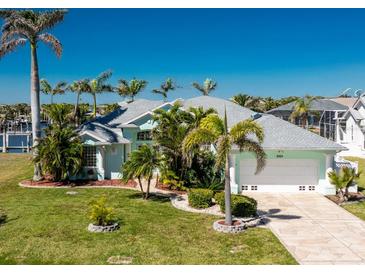 Inviting single Gathering home showcasing a well-manicured lawn, mature palms and a paved driveway leading to a two-car garage at 9325 Saint Paul Dr, Port Charlotte, FL 33981