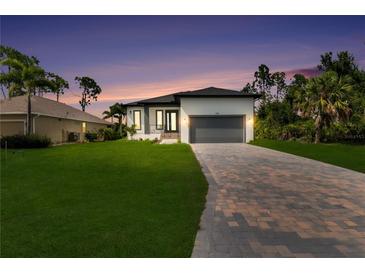 Beautiful single-Gathering home featuring a manicured lawn and brick paver driveway under a gorgeous sunset sky at 280 Antis Dr, Rotonda West, FL 33947