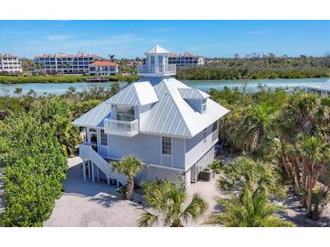 Beautiful elevated coastal home featuring a charming cupola and balcony overlooking lush tropical landscaping at 310 Kettle Harbor Dr, Placida, FL 33946