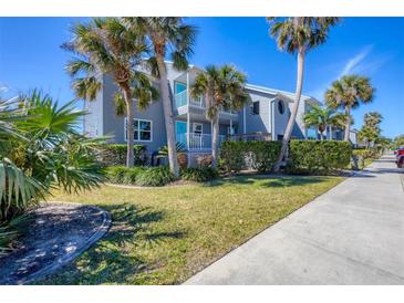 Inviting condo complex with tropical landscaping, light blue painted siding, and charming outdoor spaces at 4410 Warren Ave # 217, Port Charlotte, FL 33953