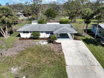 An elevated view showcasing a well-maintained white house, spacious driveway, and landscaped front yard at 1493 Kathleen Pl, Englewood, FL 34223